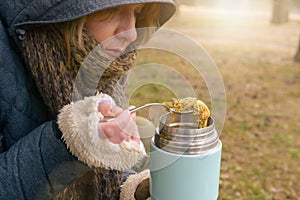 Woman is eating a warm meal from a thermos