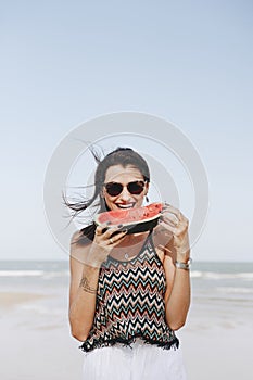 Woman eating watermelon at the beach