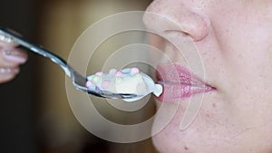 Woman eating yogurt and cottage cheese with cereal. Close up female mouth eats for breakfast dairy product.