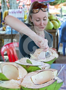 The woman eats coconut pulp in street roadside cafe