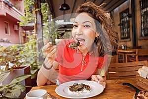 Woman eats dolma, a traditional Armenian and Georgian dish made of minced meat wrapped in grape leaves