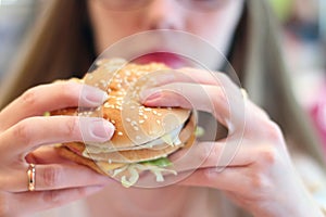 Woman eats fresh appetizing hamburger