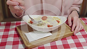 A woman eats hot julien with turkey or chicken fillet under a layer of cheese and cream sauce.