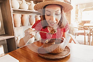 Woman eats kharcho soup from Georgian cuisine or Hungarian meat goulash in a rustic restaurant