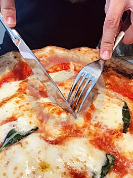 Woman eats with knife and fork a pizza Margherita