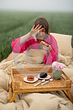 WOman eats sweets while waking up on field outdoors