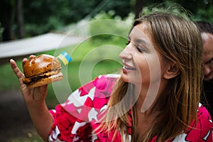 Woman eatting delicious burger while sitting at terrace in Ukraine. summer vacation travel picnic.