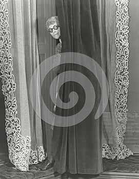 Woman eavesdropping from behind curtain