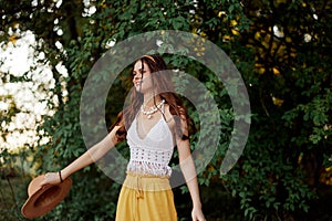 A woman in eco-friendly clothing in a hippie look dances in nature in the park and smiles at the world. The concept of