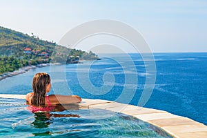 Woman at edge of infinity swimming pool with sea view