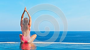 Woman at edge of infinity swimming pool with sea view