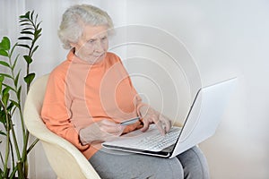 A woman of eighty years working on a laptop at home