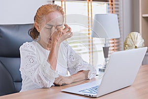 Woman elderly eyes pain from Asthenopia stress tired sinus suffer fatigue from hard work with computer screen photo