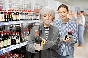 Woman with elderly mother discussing choice of soy sauce at Asian store
