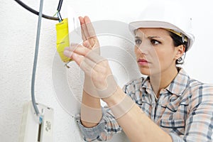 woman electrician installing switch in new house