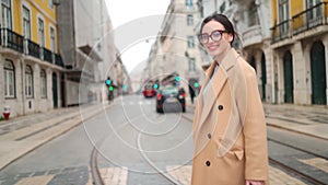 Woman in elegant beige coat crossing street in European city