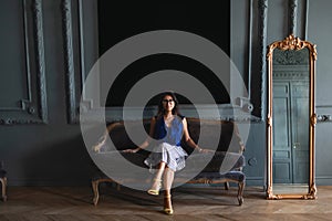 Woman in elegant clothes sitting on sofa in modern interior