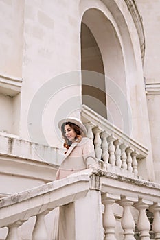 woman in elegant coat and hat against an intricate architectural backdrop, harmoniously blending modern fashion with