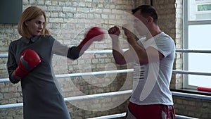 Woman in elegant dress, boxing gloves training at boxing ring with trainer