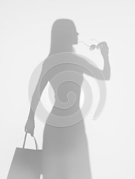 Woman elegantly holding a pair of sunglasses, silhouette