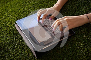 Woman Emailing And Texting With Tablet Computer On Grass