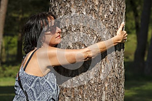 Beautiful woman hugging a tree with eyes closed