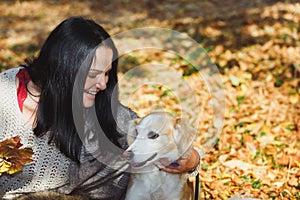 Woman embracing a dog in autumn forest