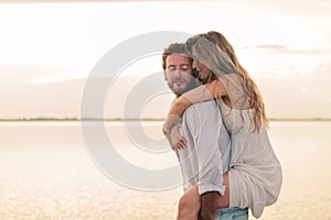 Woman embracing her man from behind at sunset