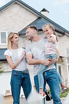 woman embracing husband while he holding daughter inf front of new photo