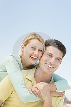 Woman Embracing Man From Behind Against Clear Blue Sky