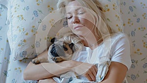 Woman embracing the puppy pug laying in the bed