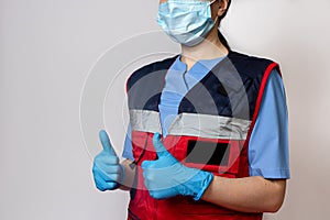 Woman emergency medicine doctor in gloves shows thumbs up.
