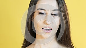 Woman with emotion of patience bites lip on yellow background. Slowly