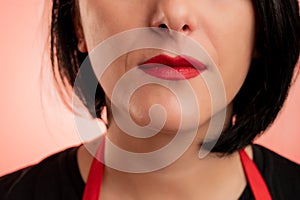 Woman employed at supermarket with red apron and black t-shirt, close-up red lips