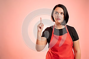 Woman employed at supermarket with red apron and black t-shirt has a good idea