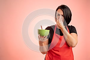 Woman employed at supermarket with red apron and black t-shirt holding a bowl of soup that smells bad