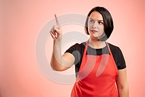 Woman employed at supermarket with red apron and black t-shirt presses a virtual button