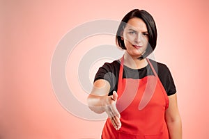 Woman employed at supermarket with red apron and black t-shirt shaking hand