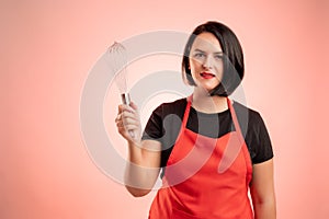 Woman employed at supermarket with red apron and black t-shirt showing metal wire in her hand