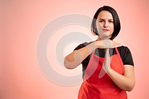 Woman employed at supermarket with red apron and black t-shirt showing time out