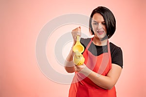 Woman employed at supermarket with red apron and black t-shirt squeeze a lemon