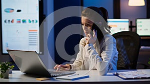 Woman employee speaking at phone while working at laptop