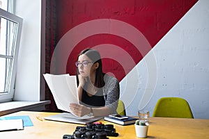 Woman employer in glasses reading resume during work day in enterprise