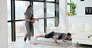 Woman encouraging husband doing push up at home