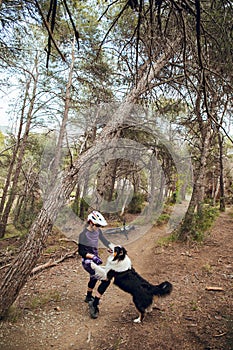 Woman with enduro mtb bike playing through the woods with her australian shepherd dog