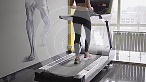 A woman is engaged in athletic walking on a treadmill in a fitness club.