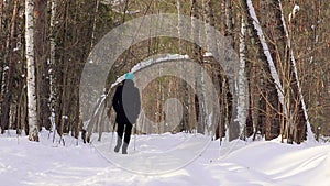 A woman is engaged in Nordic walking with sticks in the winter forest. Cardio workout