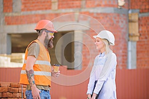 Woman engineer and brutal builder communicate construction site background. Construction team communication concept