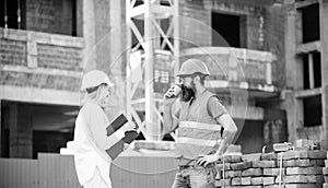 Woman engineer and brutal builder communicate construction site background. Construction team communication concept