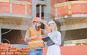 Woman engineer and builder communicate at construction site. Discussing plan. Construction team communication concept